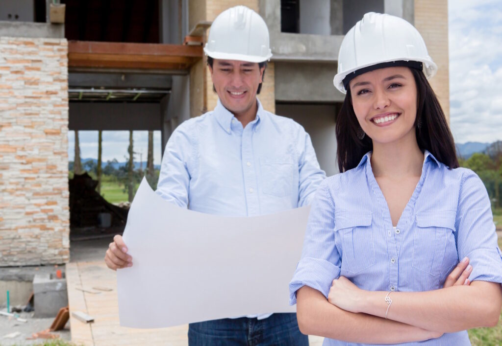 A man, who is smiling, is looking at the home building design plans. A women, who is also smiling, is standing with her hands crossed, CK Contracting, Custom Home Builders, Mt. Pleasant, S.C.