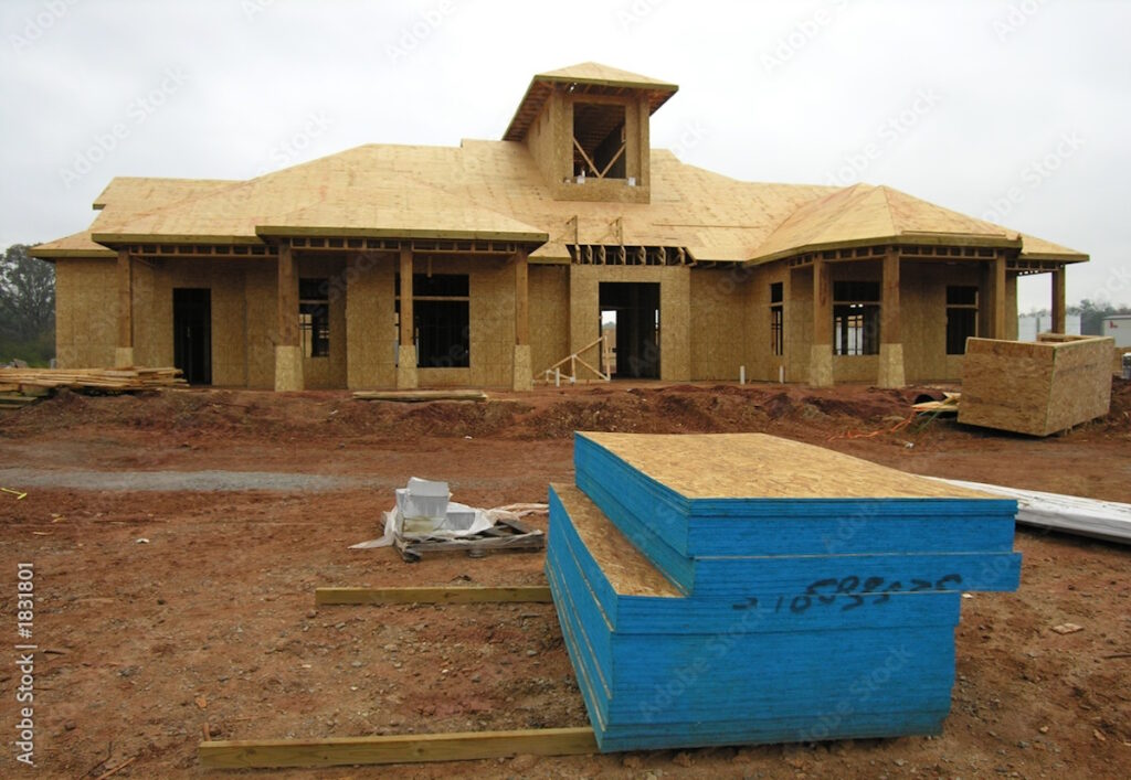 A stage of lumber placed on the dirt ground in front of a new house being built, CK Contracting, General Contractor for New Home Construction in Charleston, S.C.